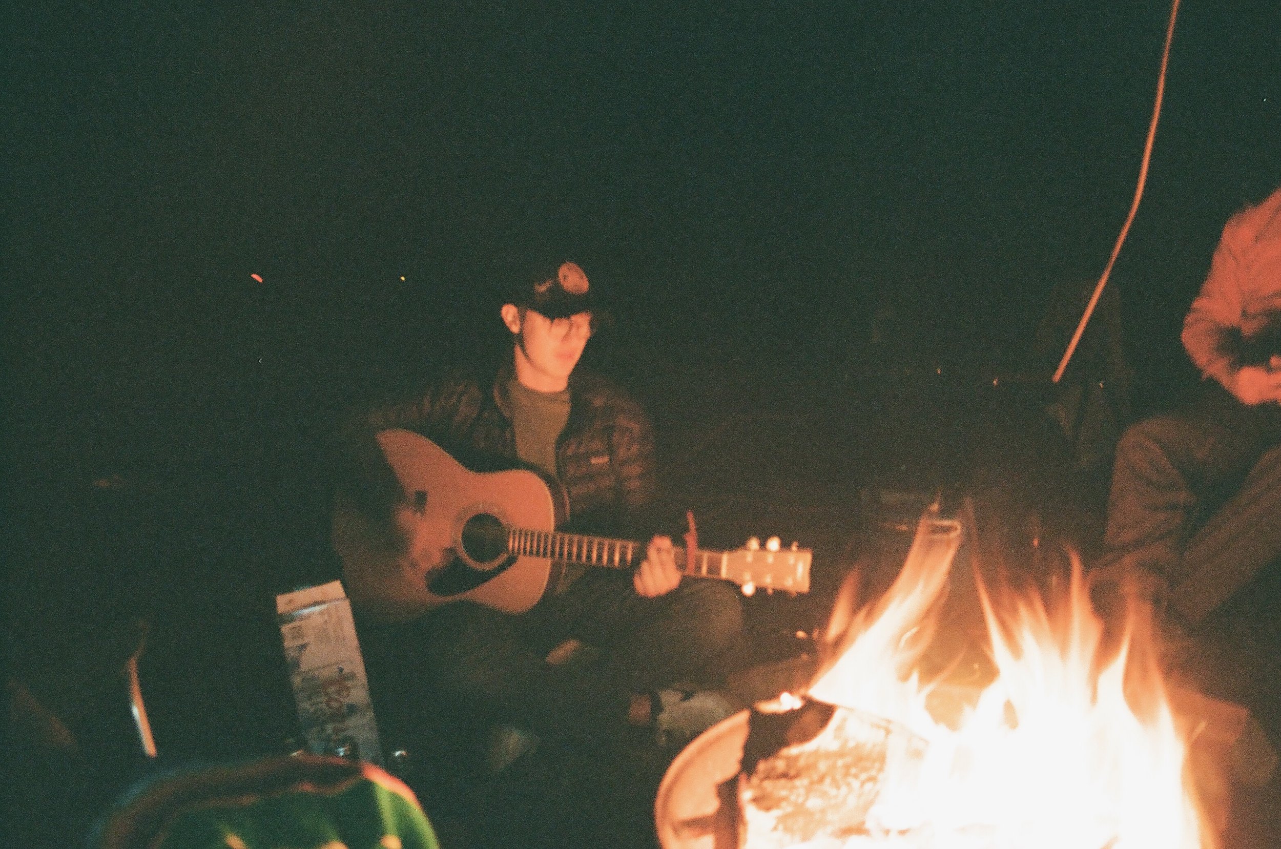 Alan playing a guitar next to a campfire